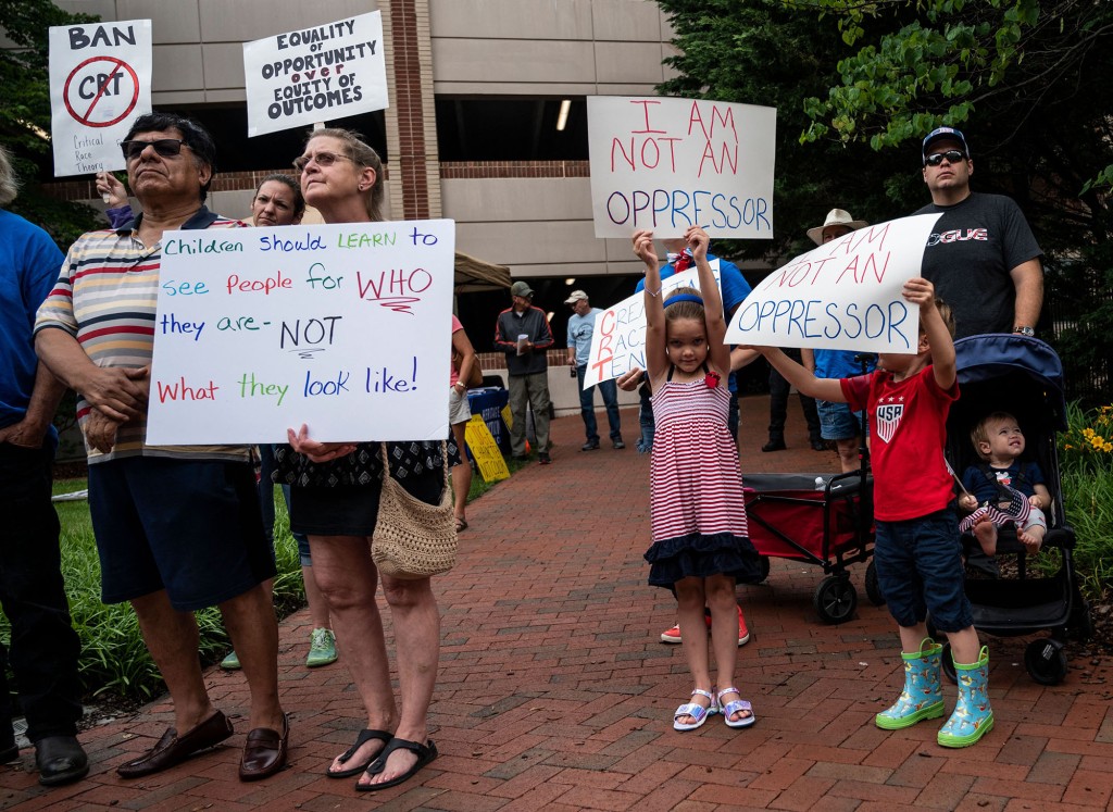 People hold up signs during a rally against "critical race theory" (CRT) being taught in schools at the Loudoun County Government center in Leesburg, Virginia on June 12, 2021