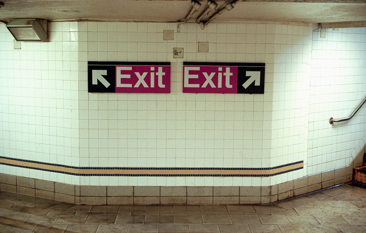 Two Subway Exit Signs Pointing in Opposite Directions